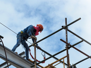 Construction workers working on scaffolding, Man Working on the Working at height with blue sky at construction site