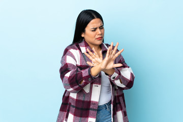 Young latin woman woman isolated on blue background nervous stretching hands to the front