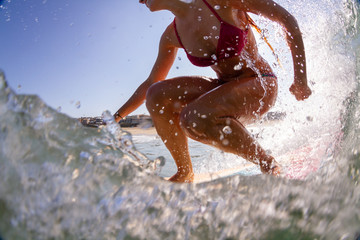 a young woman in bikini riding a wave on a surfboard