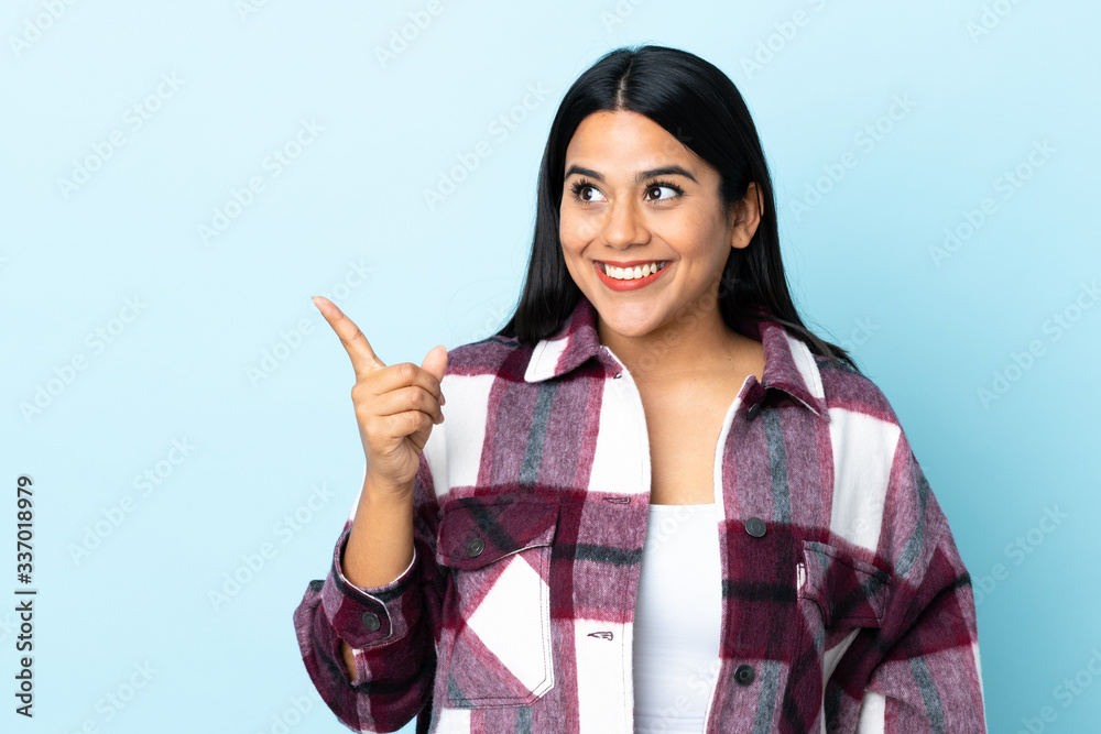 Wall mural Young latin woman woman isolated on blue background intending to realizes the solution while lifting a finger up