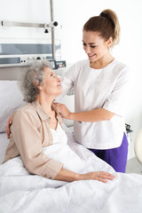 Obraz premium Woman with Alzheimer's disease lying in bed receives nurse care. Treating and caring for the elderly with Alzheimer's disease