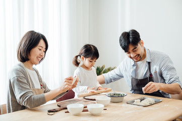 Fototapeta premium Mom and Dad and daughter at home dumplings