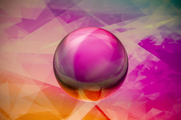 Crystal glass ball is lying on a stone surface on the colorful abstract background.