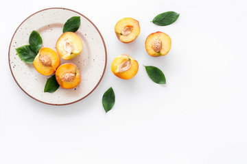 Healthy food. Ripe sliced peaches on plate on white table top-down copy space