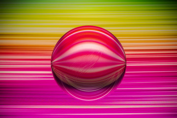 Crystal glass ball is lying on a stone surface on the colorful abstract background.