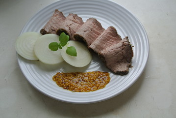 On a white plate, slices of chopped beef roast beef and salad with sauce