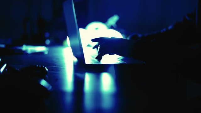 A computer programmer or hacker prints a code on a laptop keyboard to break into a secret organization system.