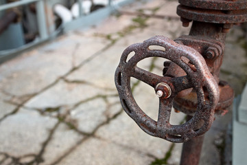 Industrial pipeline and valve close up, blur concrete background. Old rusty control equipment, abandoned plant industry with copyspace