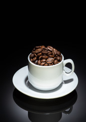 Cup with coffee beans on a dark background