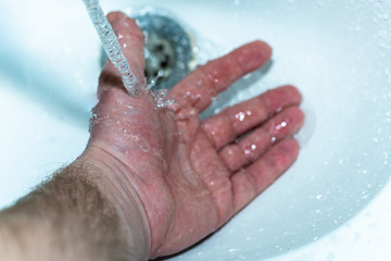 Male hand. Hand washing with water in the sink.