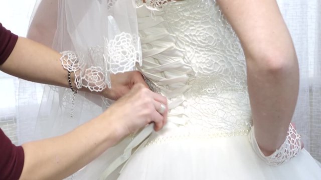 bride tightening her corset on her wedding dress