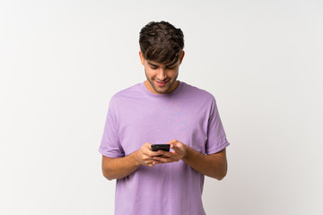 Young handsome man over isolated white background sending a message with the mobile