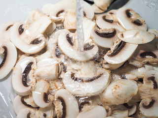 Sliced white champignons washed in water and ready for cook