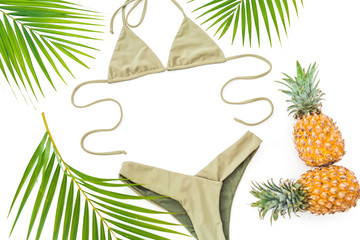 Tropical holiday concept with pineapple, palm leaves and bikini swimwear on white background. Flat...