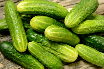 Fresh cucumbers lie together on a wooden table. The texture of green vegetables.