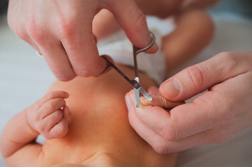 Father cuts the newborn’s nails. Manicure a child close-up. Newborn baby care concept.