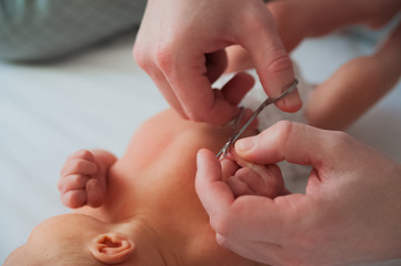 Father cuts the newborn’s nails. Manicure a child close-up. Newborn baby care concept.