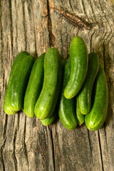 Fresh cucumbers lie together on a wooden table. The texture of green vegetables.