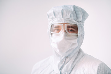 Portrait of a male doctor of European appearance in a medical mask, protective glasses and chemical suit.