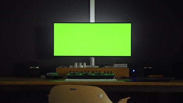 Professional 21 9 monitor for color grading, photo retouching or graphic motion design. Green chroma key screen set up. Spinning director chair for movie editing work or studio agency projects