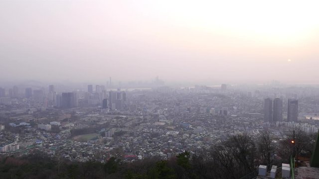 Seoul Yongsan gu panorama from height of Nam mountain, thick foggy air at evening time, smog over Asian metropolis. Low rise buildings on foreground, dense build residential area. Several tall towers