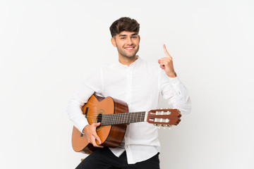 Young handsome man with guitar over isolated white background pointing up a great idea