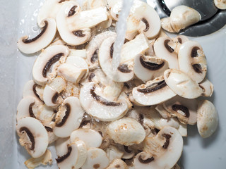 Sliced white champignons washed in water and ready for cook