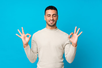 Naklejka premium Young man over isolated blue background in zen pose