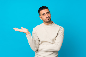 Young man over isolated blue background unhappy for not understand something