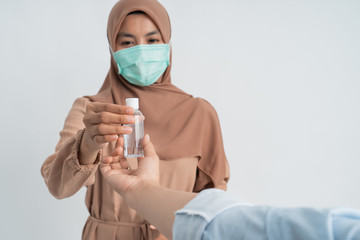 muslim woman with face masks holding hand sanitizer