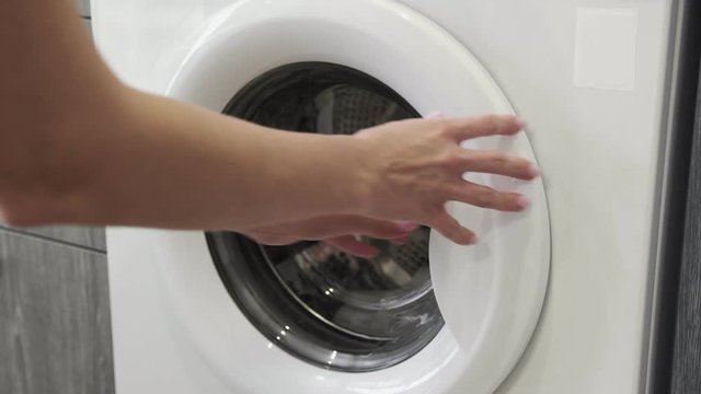 Female hand put WHITE TOWEL in laundry machine. Loading washing machine. Load clothes to washer machine. Load clothes laundry washing machine. Preparing laundry washing