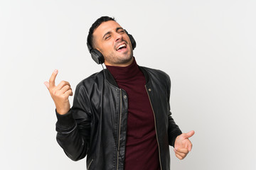 Young man over isolated white background using the mobile with headphones and dancing