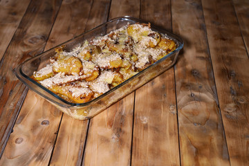 Fried banana is coated and sprinkled with cheese and cereals in a glass container on a wooden table