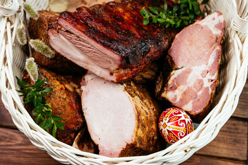 Smoked meat in a basket prepared for the Easter holidays. Closeup of large pieces of meat