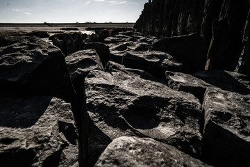 Fototapeta premium Large solid gray basalt blocks in the sunlight along the Dutch sea coast