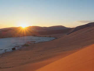 Fototapeta na wymiar Sunrise starburst near Deadvlei in Sossusvlei area, southern part of the Namib Desert, Namibia