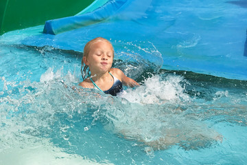 Little girl on water slide at aquapark.