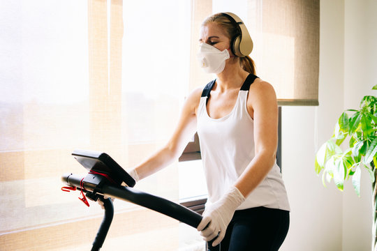 A Girl With Mask And Gloves Slim Athlete Does Exercise At Home Running On The Treadmill. Workout.