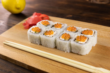 Sushi rolls with red caviar of salmon and cream cheese on wooden board