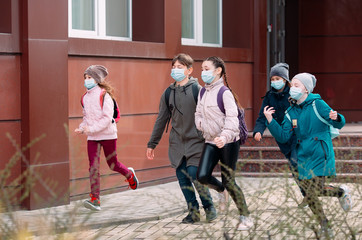 Children students in medical masks leave the school.