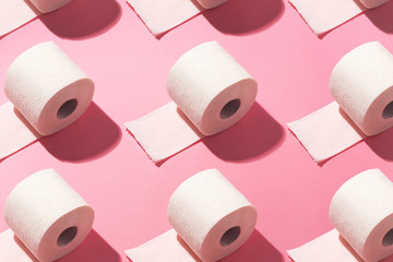 Toilet paper rolls laid out in pattern, on top of pink background.