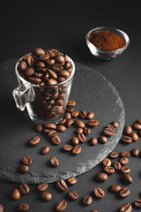 Cup of coffee beans on a round slate and ground coffee