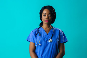 Portrait of a serious female doctor or nurse wearing blue scrubs uniform and stethoscope, isolated on blue background