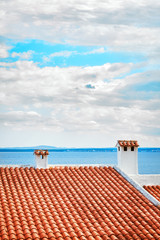 Old ceramic tile roof with seascape in background, Mallorca, Spain.