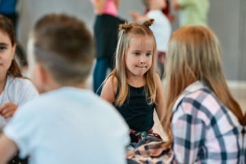 Portrait of children talking with each other while sitting on the floor and having a break in the dance studio