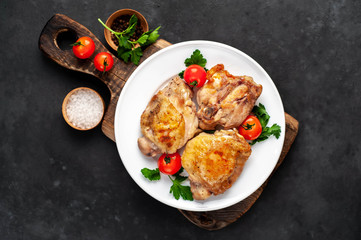 grilled chicken thighs on a white plate with spices on a stone background