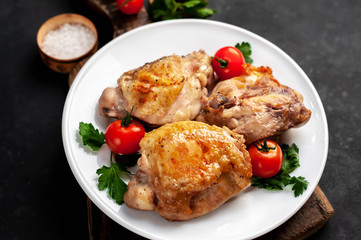 grilled chicken thighs on a white plate with spices on a stone background