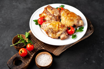 grilled chicken thighs on a white plate with spices on a stone background