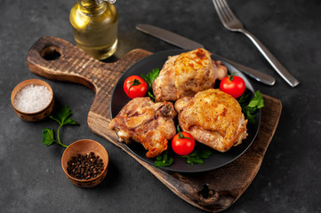 grilled chicken thighs on a black plate with spices on a stone background