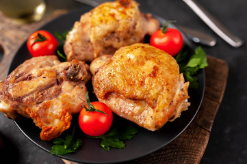 grilled chicken thighs on a black plate with spices on a stone background